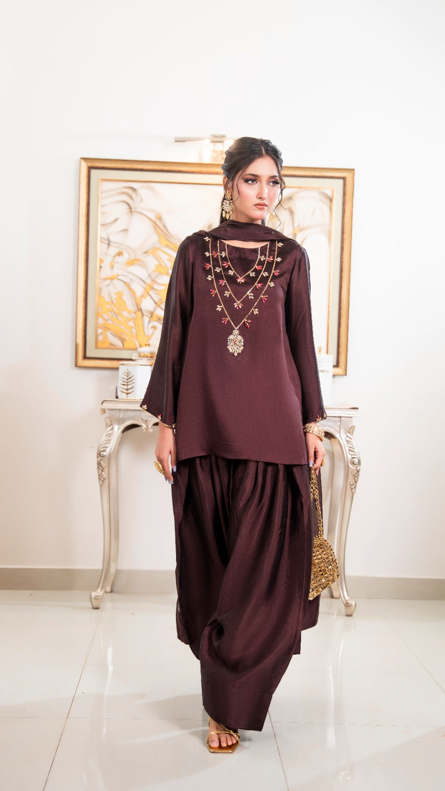 Shop Gilded Mala by FAMA by Sana Sarah's, a stunning 3-piece dark brown silk suit featuring gold hand-embroidered mala necklace detailing, dhoti pants, and a chiffon dupatta.