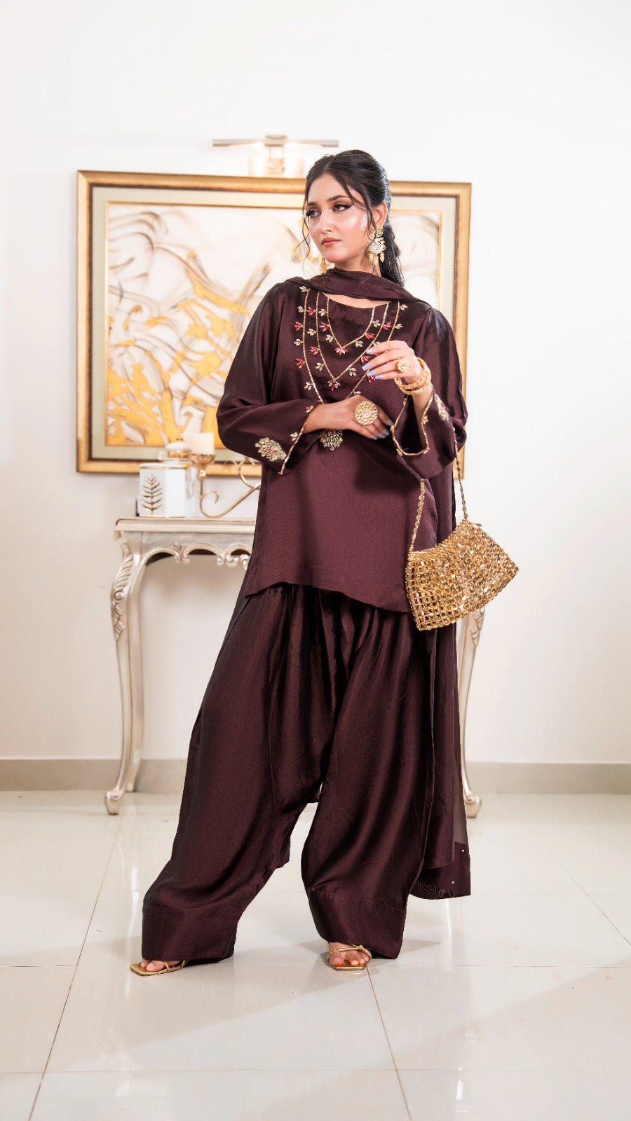 Shop Gilded Mala by FAMA by Sana Sarah's, a stunning 3-piece dark brown silk suit featuring gold hand-embroidered mala necklace detailing, dhoti pants, and a chiffon dupatta.