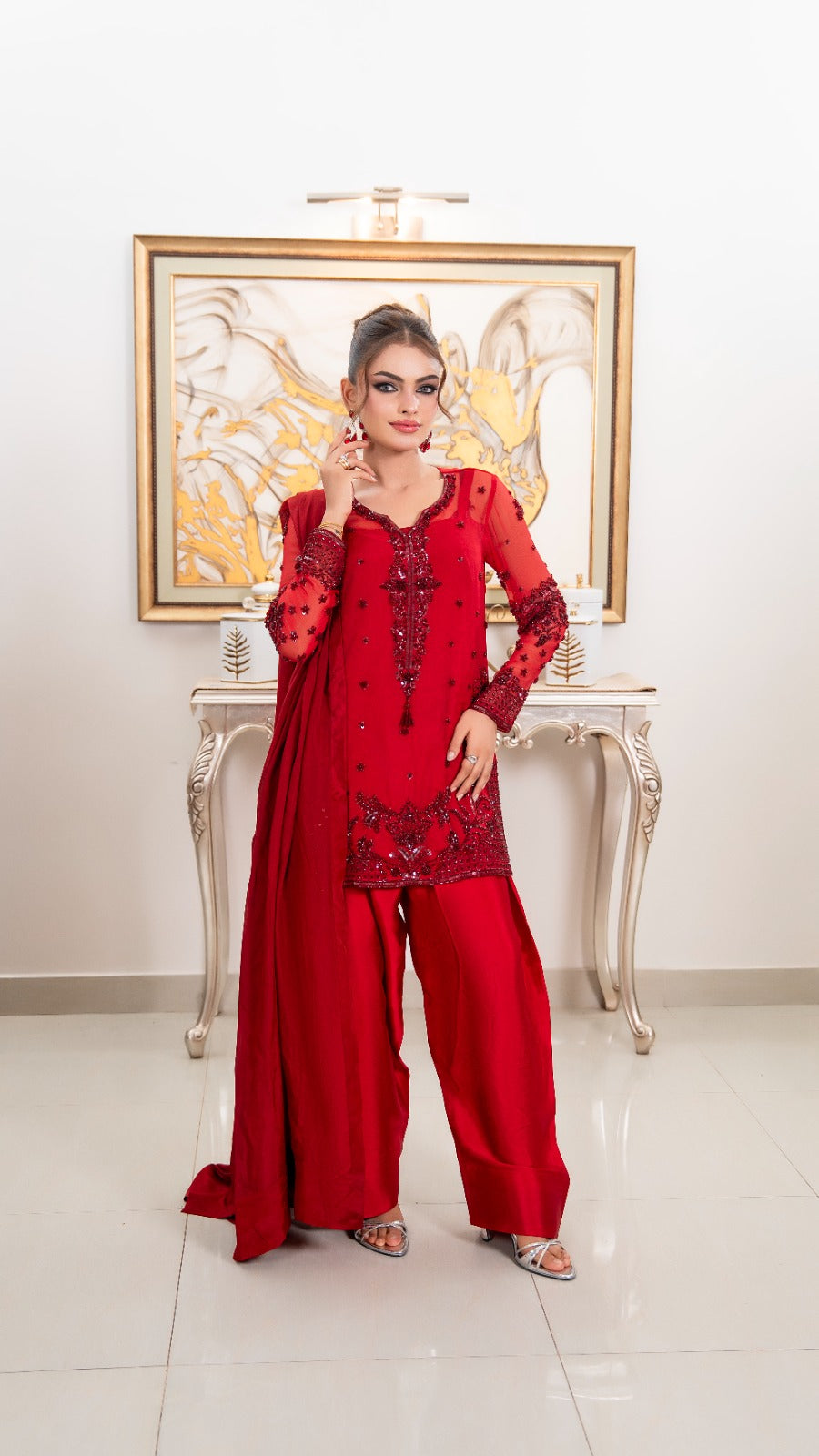 Shop Ruby by FAMA by Sana Sarah's, a stunning 3-piece ruby red hand-embellished festive outfit featuring a detailed chiffon shirt, silk flared trousers, and a draped dupatta.